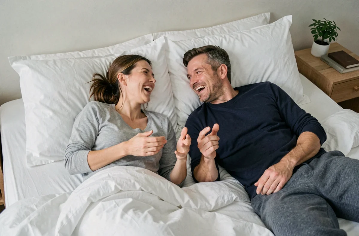 Couple détendu partageant des fous rires dans leur chambre lors d'une soirée complice à la maison